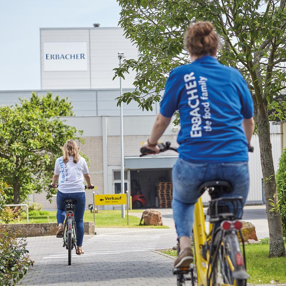 Zwei Kolleginen fahren auf dem Fahrrad über das Werksgelände.