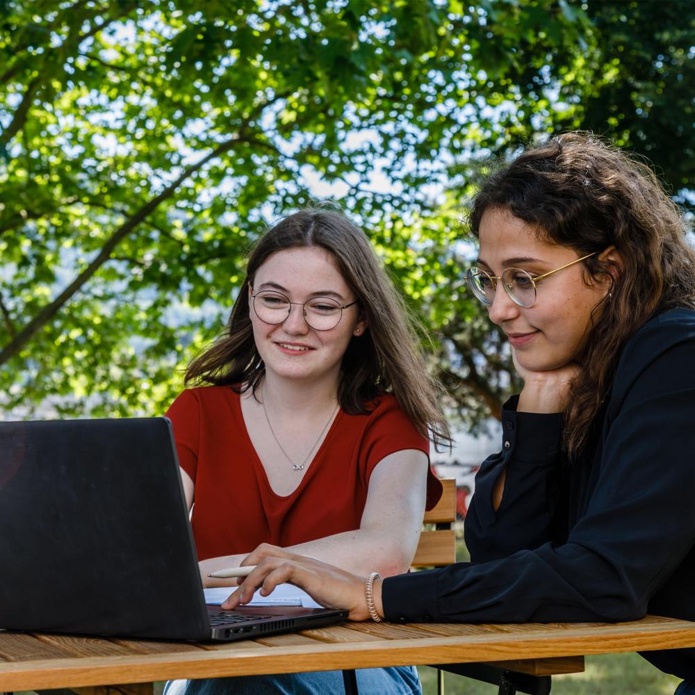 Zwei Mitarbeiterinnen schauen in den Laptop. Sie sitzen dabei im ff Park.