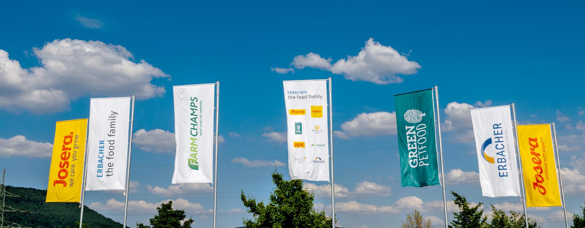 Fahnen vor dem Werksgelände mit allen Logos der food family Marken.