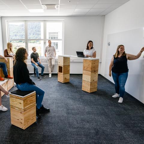 Zwei Mitarbeitende stehen am Whiteboard und erklären grafisch den anderen Kollegen etwas.